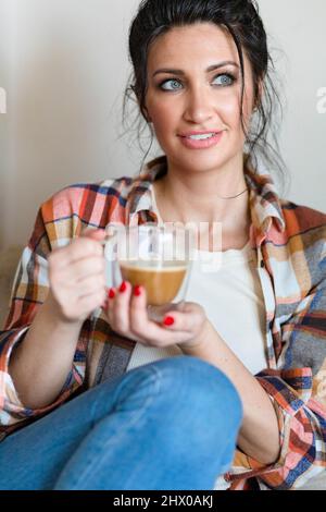 Blauäugige Frau mittleren Alters, die mit einer Tasse Kaffee sitzt Stockfoto