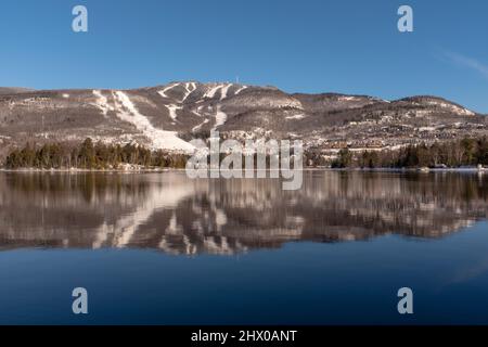 Mont-Tremblant Skipisten spiegeln sich in einem See, aufgenommen an einem sonnigen Wintertag Stockfoto