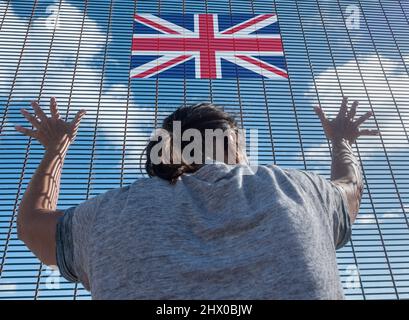 Rückansicht einer Frau bei der Grenzzaunkontrolle mit britischer Flagge. Britische Einwanderung, Visapolitik, Ukraine, Russland Konflikt Flüchtling, Brexit, EU-Grenze... Konzept Stockfoto