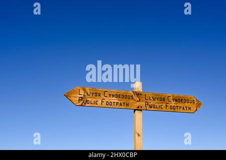 Zweisprachiges Holzschild auf einem öffentlichen Fußweg gegen einen tiefblauen Himmel. Speicherplatz kopieren. Keine Personen. Stockfoto