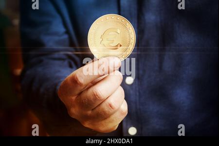Euro EUR Währung in EU Symbol goldene Münze in der Hand abstraktes Konzept. Stockfoto