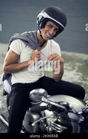 Er liebt seine Fahrt im Vintage-Stil. Ein hübscher junger Mann, der auf seinem Motorrad sitzt. Stockfoto