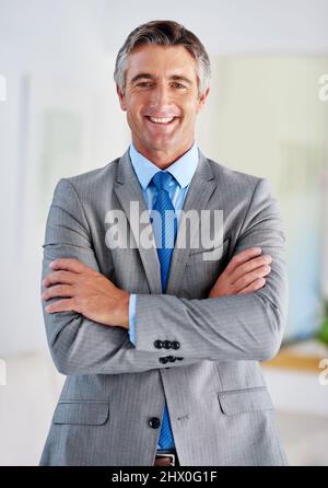 HES der vollendete Corporate Pro. Porträt eines lächelnden, reifen Geschäftsmannes, der mit gekreuzten Armen steht. Stockfoto