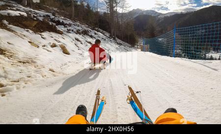 Standpunkt eines Kindes Rodeln mit Vater, Reiten eines Holzschlittens auf dem Hügel an sonnigen klaren Wintertag. Stockfoto