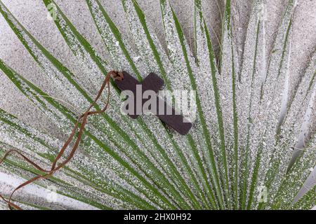 Ash Wednesday und Fastenkonzept. Christian Kreuz auf dem Palmblatt. Christliches Religionskonzept. Flach liegend. Stockfoto