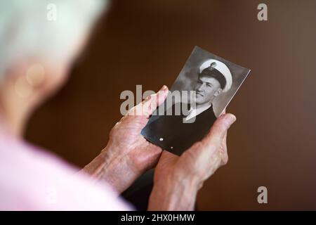 Eines Tages werden wir uns wieder treffen. Eine beschnittene Aufnahme einer älteren Frau mit einem alten Schwarz-Weiß-Foto eines Mannes. Stockfoto