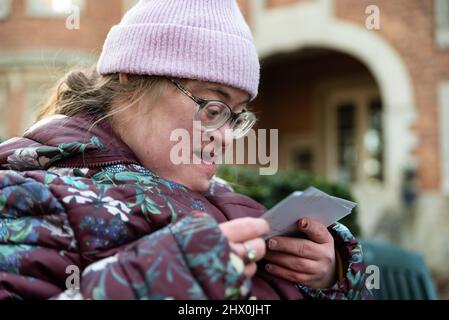 Außenportrait einer 39-jährigen weißen Frau mit Down-Syndrom beim Betrachen gedruckter Bilder Stockfoto