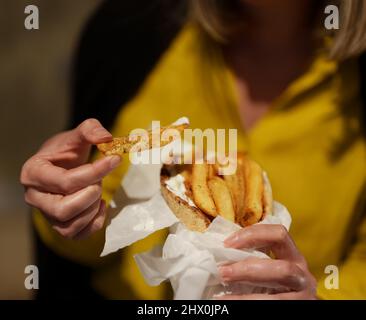 Frau isst Pita mit pommes frites. Stockfoto