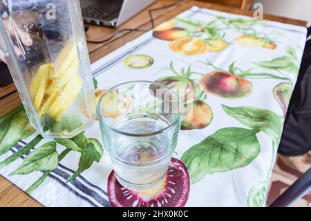Krug mit Zitronenscheiben neben einem Glas auf einem Obsttischdecke auf einem Holztisch mit Kopierfläche. Stockfoto