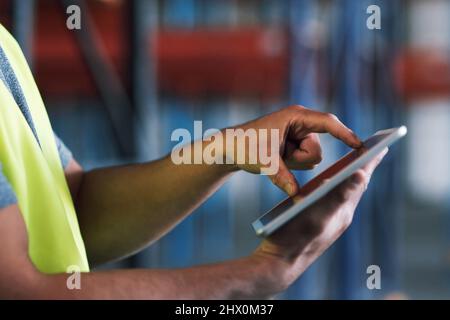 Bleiben Sie in Verbindung, und halten Sie die Sicherheitsbestimmungen ein. Aufnahme eines Baumeisters mit einem digitalen Tablet während der Arbeit auf einer Baustelle. Stockfoto
