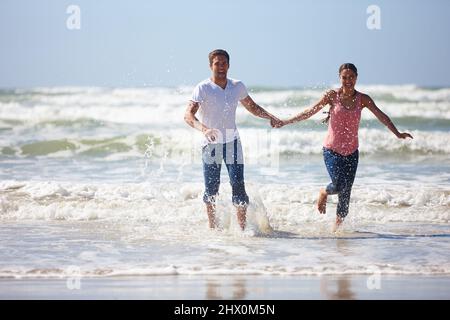 Sie bringt den Spaß in mir hervor. Aufnahme eines jungen Paares, das am Strand verspielt ist. Stockfoto