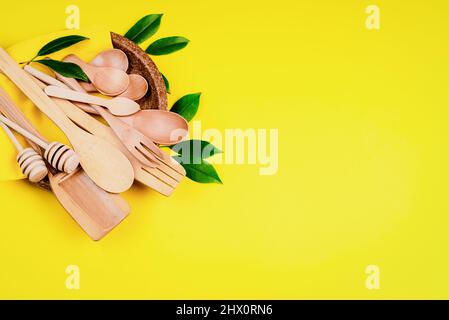 RecyclingkonzeptEinwegbesteck auf einem gepressten Pappteller auf gelbem Grund.Umweltfreundliche Einwegutensilien aus Bambusholz und Papier Stockfoto