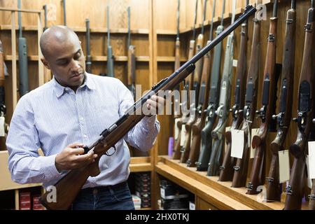 Porträt eines selbstbewussten Mannes in der Waffenhandlung mit Gewehr Stockfoto