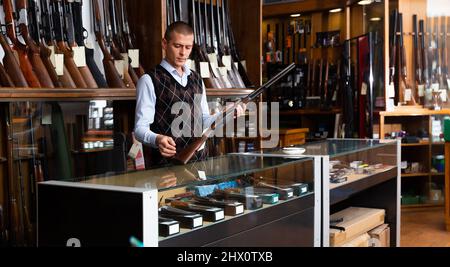 Der Erwachsene Besitzer des Waffenladens demonstriert ein seltenes Sammlergewehr Stockfoto