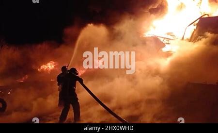 Zhytomyr, Ukraine. 8. März 2022. Der staatliche Notdienst der ukrainischen Arbeiter in der Region Schythomyr bekämpft nach Luftangriffen russischer Streitkräfte ein Feuer in einem Öllager. Zwei halbleere Tanks von 17 an der Ölbasis im Dorf Tschernyakhiv brannten. Die Stadt Zhytomyr, die 140 km westlich von Kiew liegt, und ihre Umgebung wurden regelmäßig von russischen Truppen angegriffen, als sie die ukrainische Hauptstadt umzingeln. Bis Dienstag war das Feuer gelöscht worden. (Bild: © State Emergency Service of Ukraine/ZUMA Press Wire Service) Stockfoto