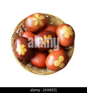 Draufsicht auf den Osterkorb. Natürlich gefärbte Eier mit Zwiebelschalen im Korb isoliert auf weißem Hintergrund Stockfoto