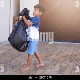 Zeit, den Müll zu entsorgen. Aufnahme eines kleinen Jungen, der den Müll zu Hause herausnimmt. Stockfoto