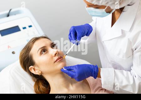Frau, die in der Klinik eine kosmetische Gesichts-Injektion erhalten hat Stockfoto