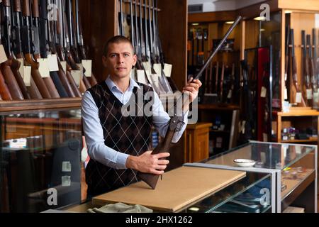 Der Besitzer des Waffenladens zeigt ein seltenes Sammlergewehr Stockfoto