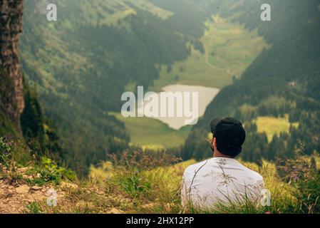 Ein Mann sitzt nach einer schönen Wanderung auf einem Berg und bewundert die Natur Stockfoto