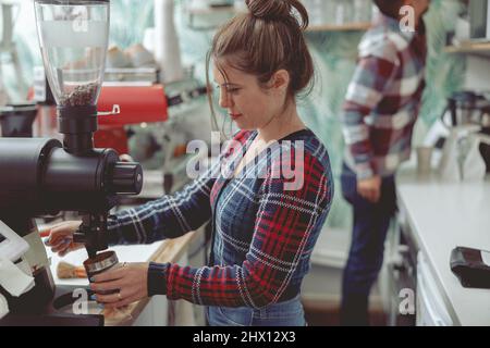 Barista, die in einem Café in der Nähe der Kaffeemühle arbeitet Stockfoto