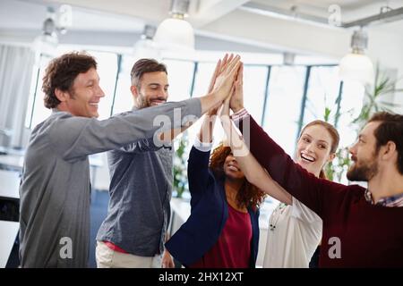 Ein weiteres Projekt, ein weiterer zufriedener Kunde. Aufnahme eines Teams von Geschäftsleuten, die sich im Büro gegenseitig eine hohe fünf geben. Stockfoto