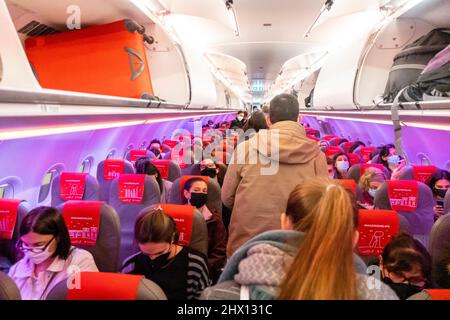 Passagiere, die im Flugzeug von Iberia Express durch den Gang laufen, violettes Licht Stockfoto