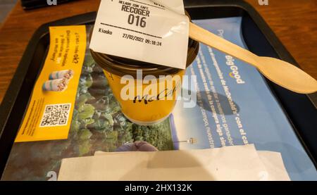 Café americano in einer Papiertasse auf einem Tablett mit Holzrührer auf einem Tisch im McDonalds Café im Flughafen Madrid, Spanien Stockfoto
