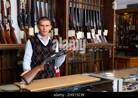 Porträt eines Verkäufers in einem Waffenladen mit einer Kugelpistole in den Händen Stockfoto