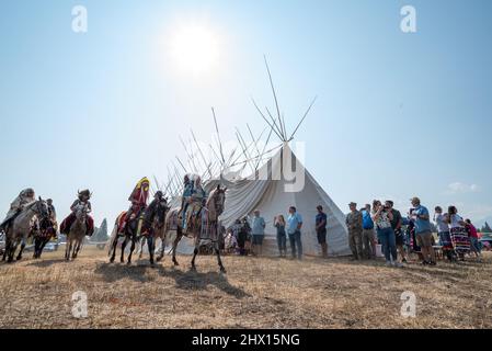 Nez Perce Reiter in einer Prozession um ein Langhaus in am'saaxpa, Wallowa Valley, Oregon. Stockfoto