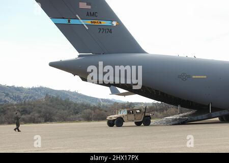 Ein US-Luftwaffenflieger mit dem 3. Airlift Squadron, Dover Air Force Base, Delaware, führt einen Humvee, der dem 7. Marine Regiment, 1. Marine Division, zugewiesen wurde, aus einem C-17 Globemaster III während einer Kommandoübung in Fort Hunter Liggett, Kalifornien, 1. März 2022. Diese Entwicklung bot Marines die Gelegenheit, die zweckmäßige Einrichtung eines Regimentshauptquartiers zu üben, um die Kontrolle und Kontrolle von verteilten Standorten aus zu ermöglichen. (USA Marine Corps Foto von Sgt. Jailine L. AliceaSanago) Stockfoto