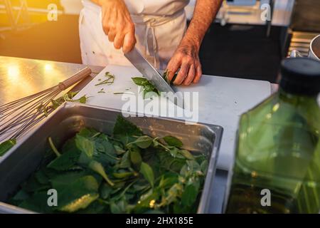 Nahaufnahme der Hände eines professionellen Küchenchefs, der frischen Orangen hackt Stockfoto