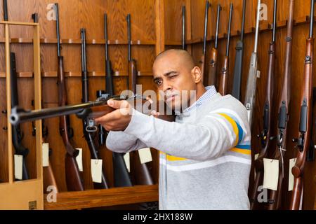 Porträt eines selbstbewussten Mannes in der Waffenhandlung mit Gewehr Stockfoto