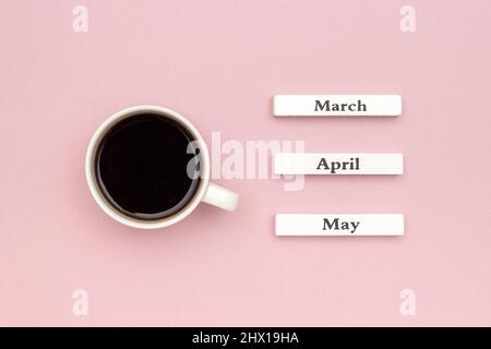 Holzkalender Frühlingsmonate März April Mai und Tasse schwarzen Kaffee auf pastellrosa Papier Hintergrund gerichtet Mai. Konzept Hallo May Kreativ-Top Stockfoto