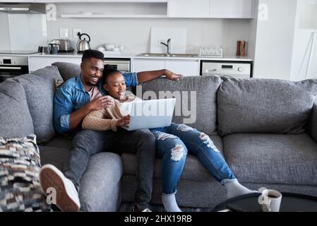 Waren heute nur noch kühl. Aufnahme eines jungen Paares, das zu Hause einen Laptop auf einem Sofa benutzt. Stockfoto