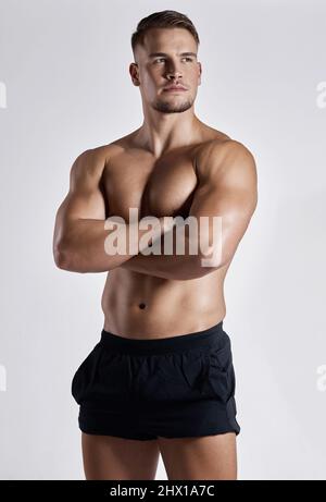 Er nimmt Fitness ernst und das zeigt sich. Aufnahme eines muskulösen jungen Mannes, der vor weißem Hintergrund posiert. Stockfoto