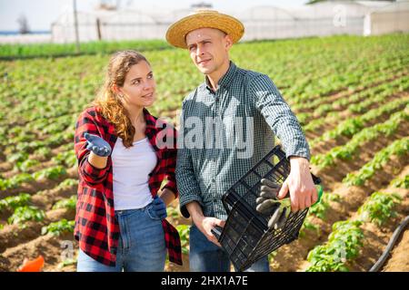 Zwei Bauern unterhalten sich während einer Arbeitspause auf dem Feld untereinander Stockfoto