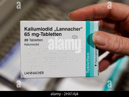 08. März 2022, Sachsen, Leipzig: Ein Apotheker nimmt eine Packung hochdosierter Jodtabletten aus einem Versorgungsschrank. Die erhöhte Nachfrage nach Jodtabletten angesichts des Krieges in der Ukraine könnte zu Problemen für Patienten mit Schilddrüsenerkrankungen führen. Bestimmte Präparate sind nicht mehr verfügbar, teilte der Sächsische Apothekerverband auf Anfrage mit - und warnte vor einer präventiven Einnahme von niedrig dosierten Jodtabletten. Die für die Katastrophenbekämpfung zuständigen Behörden haben dafür rund 190 Millionen Tabletten in deutlich stärkeren Dosen gelagert. Foto: Jan Woitas/dpa-Zentralbild/dpa Stockfoto