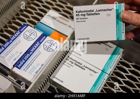 08. März 2022, Sachsen, Leipzig: Ein Apotheker nimmt aus einem Versorgungsschrank eine Packung hochdosierter Jodtabletten, daneben schwächere Dosen für Schilddrüsenerkrankungen. Die durch den Krieg in der Ukraine gestiegene Nachfrage nach Jodtabletten könnte zu Problemen für Patienten mit Schilddrüsenerkrankungen führen. Bestimmte Präparate sind nicht mehr verfügbar, teilte der Sächsische Apothekerverband auf Anfrage mit - und warnte vor einer präventiven Einnahme von niedrig dosierten Jodtabletten. Die für die Katastrophenbekämpfung zuständigen Behörden haben dafür rund 190 Millionen Tabletten in deutlich stärkeren Dosen gelagert. P Stockfoto