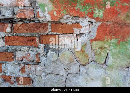 Alte Ziegelwand mit bröckelndem farbigen Putz. Hintergrund, Textur Stockfoto