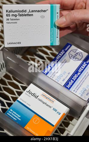 08. März 2022, Sachsen, Leipzig: Ein Apotheker nimmt aus einem Versorgungsschrank eine Packung hochdosierter Jodtabletten, daneben schwächere Dosen für Schilddrüsenerkrankungen. Die durch den Krieg in der Ukraine gestiegene Nachfrage nach Jodtabletten könnte zu Problemen für Patienten mit Schilddrüsenerkrankungen führen. Bestimmte Präparate sind nicht mehr verfügbar, teilte der Sächsische Apothekerverband auf Anfrage mit - und warnte vor einer präventiven Einnahme von niedrig dosierten Jodtabletten. Die für die Katastrophenbekämpfung zuständigen Behörden haben dafür rund 190 Millionen Tabletten in deutlich stärkeren Dosen gelagert. P Stockfoto
