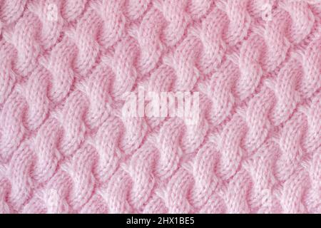 Strickstoff aus Wollgarn rosa Farbe. Stricknadeln mit Muster „Spit“, handgefertigt. Hintergrundtextur. Stockfoto