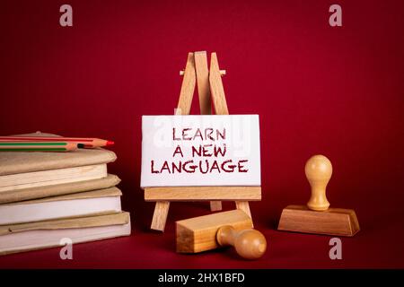 Lernen Sie eine neue Sprache. Stapel von Büchern und Briefmarken auf rotem Hintergrund. Stockfoto