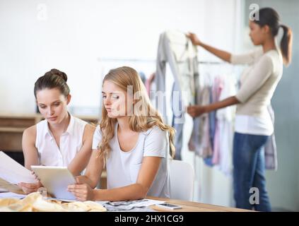 Entwicklung der neuen Produktreihe. Drei junge, multiethnische Modedesigner arbeiten in ihrem Studio. Stockfoto