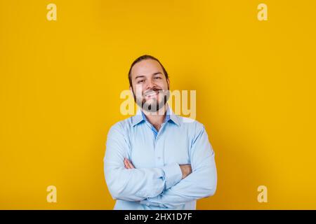 Junger lateinamerikanischer bärtiger Geschäftsmann in formeller Kleidung lächelt auf gelbem Hintergrund vor der Kamera in Mexiko-Lateinamerika Stockfoto