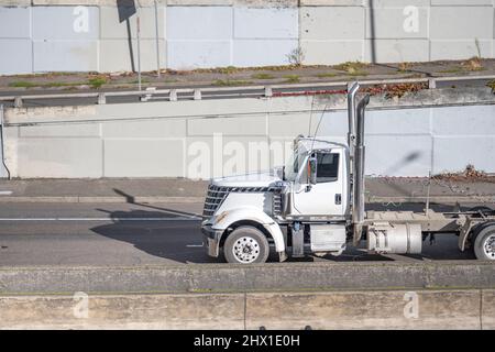 Weißer industrieller großer Rig Tag Kabine Motorhaube Sattelschlepper mit Chrom-Zubehör und hohe Auspuffrohre transportieren Ladung in Sattelauflieger läuft o Stockfoto