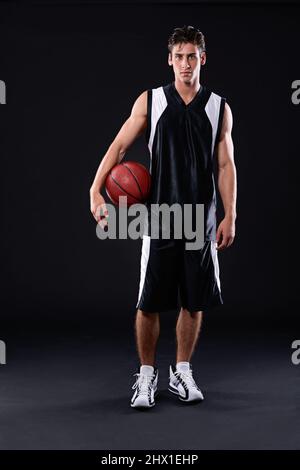 Lasst uns Ball spielen. In voller Länge Studio-Porträt eines Basketballspielers, der mit seinem Ball vor einem schwarzen Hintergrund steht. Stockfoto