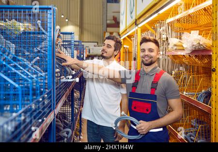 Verkäufer in einem DIY-Geschäft hilft seinem Kunden bei der Auswahl eines neuen Waschmaschinenschlauchs Stockfoto