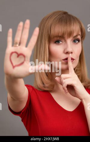 Rote Herzform auf der Handfläche der Frau mit Lippenstift gezeichnet Stockfoto