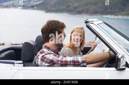 Fahren wir. Aufnahme eines jungen Paares, das in einem Cabrio die Küste entlang fährt. Stockfoto
